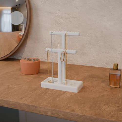 Jewellery holder on a dresser with necklaces, a bracelet and hoops on the bars and rings in the tray